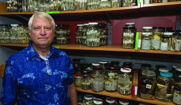 a man stands in front of specimen jars 